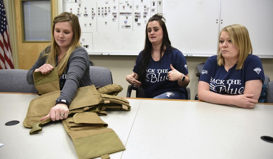 In a Tuesday, Jan. 16, 2018 photo, Lydia Hebdon, left, pulls open part of the Spartan armor vest as fellow Blue Line Ladies Foundation board members Aly Ward, center, and Anna McEwan, right, talk about the groups fundraising efforts to equip Utah law enforcement with the vests, inside Weber County Sheriff's Department in Ogden. (Sarah Welliver/Standard-Examiner via AP)