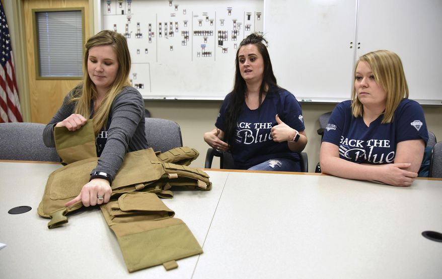 In a Tuesday, Jan. 16, 2018 photo, Lydia Hebdon, left, pulls open part of the Spartan armor vest as fellow Blue Line Ladies Foundation board members Aly Ward, center, and Anna McEwan, right, talk about the groups fundraising efforts to equip Utah law enforcement with the vests, inside Weber County Sheriff's Department in Ogden. (Sarah Welliver/Standard-Examiner via AP)