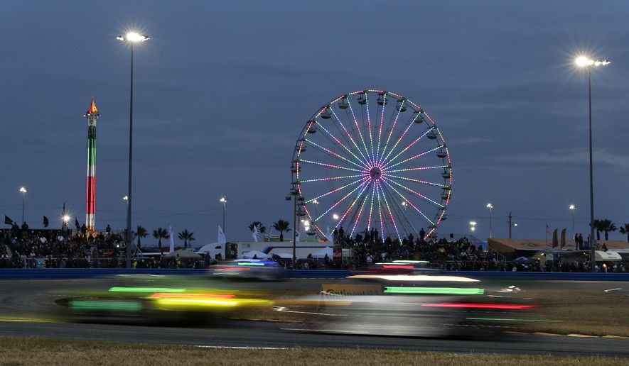 Cars head through a turn in the early evening hours during the IMSA 24-hour auto race at Daytona International Speedway, Saturday, Jan. 27, 2018, in Daytona Beach, Fla. (AP Photo/John Raoux)