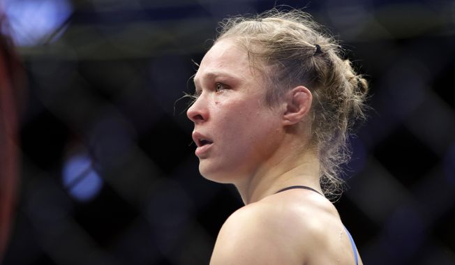 In this Dec. 30, 2016, file photo, Ronda Rousey stands in the cage after Amanda Nunes forced a stoppage in the first round of their women&#x27;s bantamweight championship mixed martial arts bout at UFC 207 in Las Vegas. (AP Photo/John Locher) ** FILE **