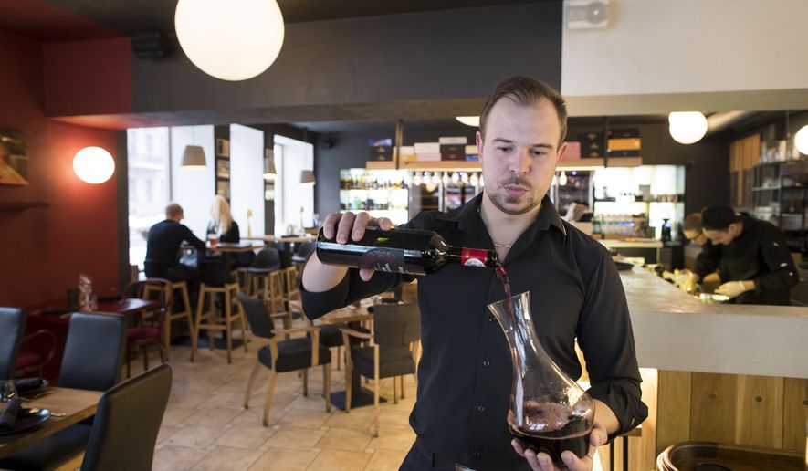 In this photo taken on Saturday, Jan. 20, 2018, a restaurant worker pours wine into decanter as bottles from Jan. 1, 2018 are no longer allowed to be displayed in restaurants after 8pm as the labels are considered advertising at the restaurant in Vilnius, Lithuania. Lithuania's new liquor law has increased the legal drinking age from 18 to 20, banned alcohol advertising and drastically curtailed opening hours for liquor stores. (AP Photo/Mindaugas Kulbis)