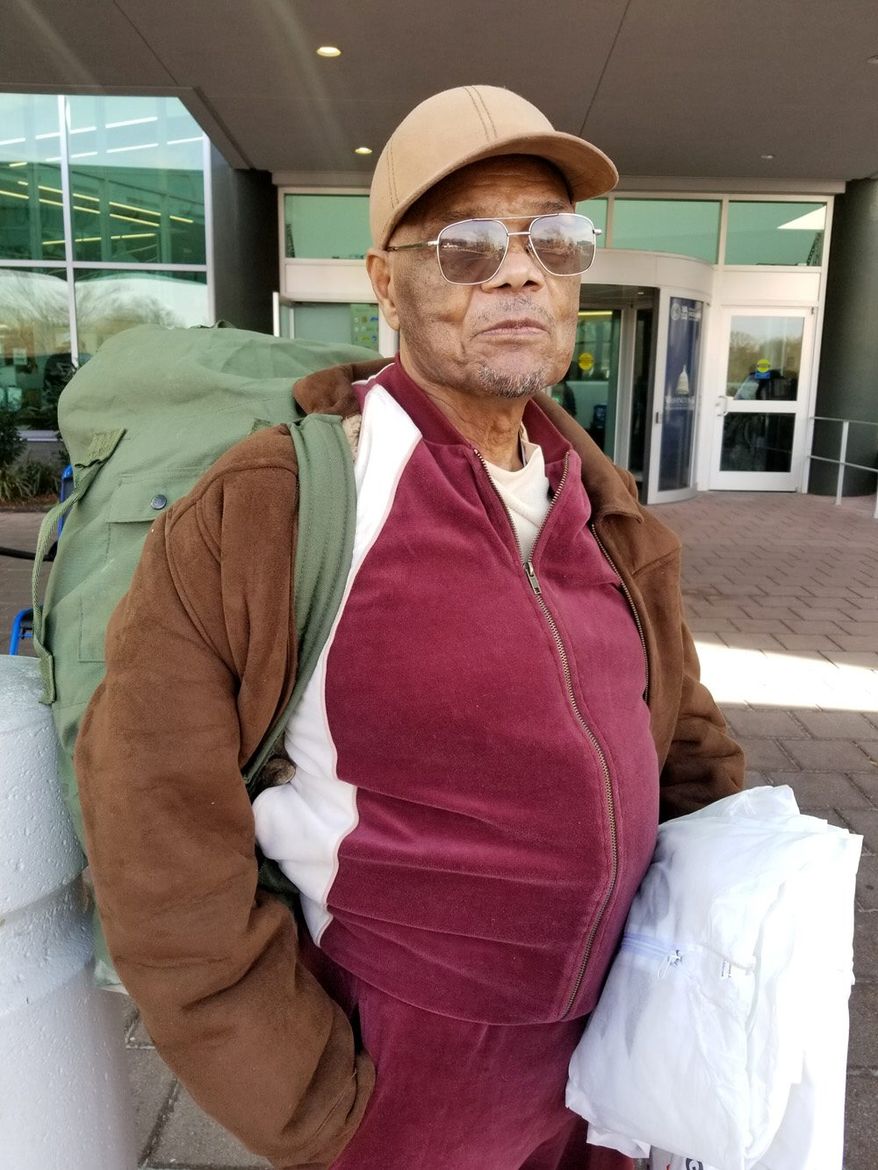 Army veteran Bernin Gibson, 82, leans his pack of donated winter clothes against a bollard near the Washington DC VA Medical Center on Saturday after the Winterhaven service fare. Mr. Gibson has attended Winterhaven since it began 24 years ago. (Julia Airey / The Washington Times)