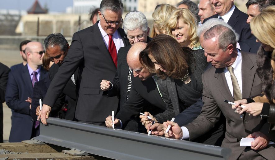 FILE - In this Jan. 6, 2015, file photo, Gov. Jerry Brown, center, and his wife, Anne Gust Brown, fourth from right, sign a portion of a rail at the California High-Speed Rail Authority groundbreaking event as Gina McCarthy, administrator of the U.S. Environmental Protection Agency, standing next to Brown at left, watches in Fresno, Calif. A bipartisan team of lawmakers are seeking a formal audit of California's high-speed rail project following a nearly $3 billion jump in costs. Democratic Sen. Jim Beall and Republican Assemblyman Jim Patterson will make their pitch for the audit Tuesday, Jan. 30, 2018, to a joint committee that will choose whether to authorize it. (AP Photo/Gary Kazanjian, File)