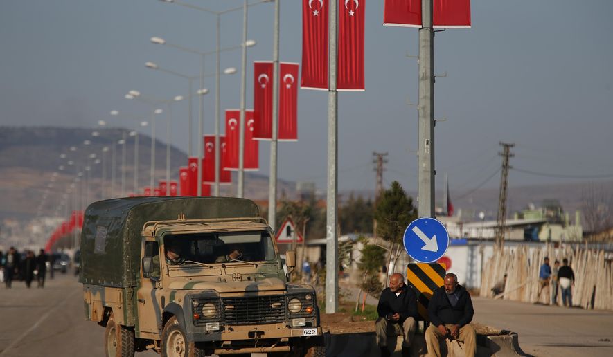 A Turkish Forces vehicles is driven past people watching at the Oncupinar border crossing with Syria, known as Bab al Salameh in Arabic, in the outskirts of the town of Kilis, Monday, Jan. 29, 2018. Renewed clashes erupted on Monday on a strategic hilltop in northwestern Syria captured by Turkish troops the day before as Syrian Kurdish militiamen try to regain control. (AP Photo/Lefteris Pitarakis)
