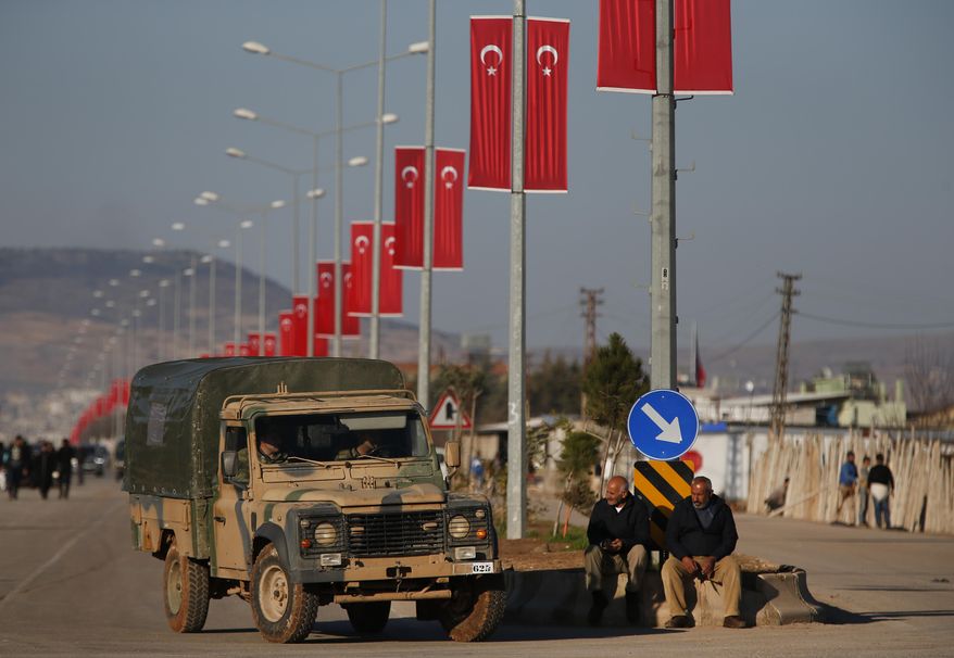 A Turkish Forces vehicles is driven past people watching at the Oncupinar border crossing with Syria, known as Bab al Salameh in Arabic, in the outskirts of the town of Kilis, Monday, Jan. 29, 2018. Renewed clashes erupted on Monday on a strategic hilltop in northwestern Syria captured by Turkish troops the day before as Syrian Kurdish militiamen try to regain control. (AP Photo/Lefteris Pitarakis)