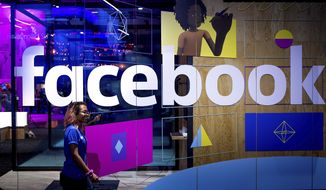 In this Tuesday, April 18, 2017, file photo, a conference worker passes a demo booth at Facebook&#39;s annual F8 developer conference, in San Jose, Calif. Facebook Inc. reports earnings Wednesday, Jan. 31, 2018. (AP Photo/Noah Berger, File)
