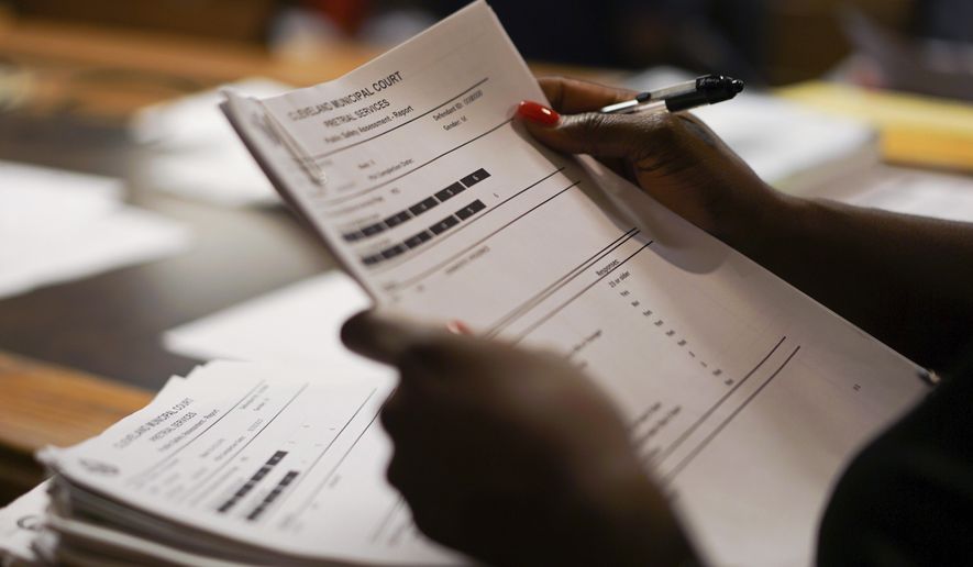 In this Aug. 30, 2017, photo, probation officer Stephanie Pope-Earley sorts through defendant files scored with risk-assessment software on the first day of the software's use in Cleveland. Cleveland Municipal Court is joining other courts across the country that are beginning to use artificial intelligence to help determine bond and parole for defendants. (AP Photo/Dake Kang)