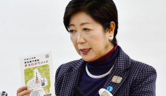 In this Friday, Jan. 26, 2018 photo, Tokyo Gov. Yuriko Koike holds a brochures of a 2018 draft budget while speaking during a press conference in Tokyo. Koike explained the city will more than double the billions it is already budgeting to stage the 2020 Tokyo Olympics. However, the International Olympic Committee and Tokyo organizers say the city’s added costs are for many projects that would have been done - with our without the Olympics. (Noriko Kawamura/Kyodo News via AP)