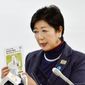 In this Friday, Jan. 26, 2018 photo, Tokyo Gov. Yuriko Koike holds a brochures of a 2018 draft budget while speaking during a press conference in Tokyo. Koike explained the city will more than double the billions it is already budgeting to stage the 2020 Tokyo Olympics. However, the International Olympic Committee and Tokyo organizers say the city’s added costs are for many projects that would have been done - with our without the Olympics. (Noriko Kawamura/Kyodo News via AP)
