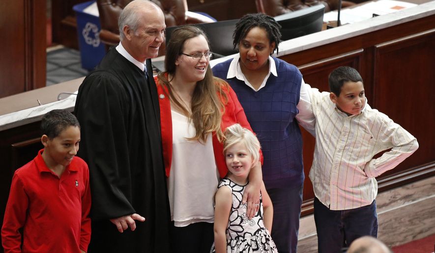 Oklahoma state Dem. Sen. Allison Ikley-Freeman, back center, D-Tulsa, poses for a photo with her wife, Dawn Ikley-Freeman, back right, State Supreme Court Chief Justice Douglas Combs, back left, and her children, Vincent Ikley, front left, Piper Freeman, front center, and Nathan Ikley, front right, after taking the oath of office on the House floor Oklahoma City, Thursday, Feb. 1, 2018. (AP Photo/Sue Ogrocki)