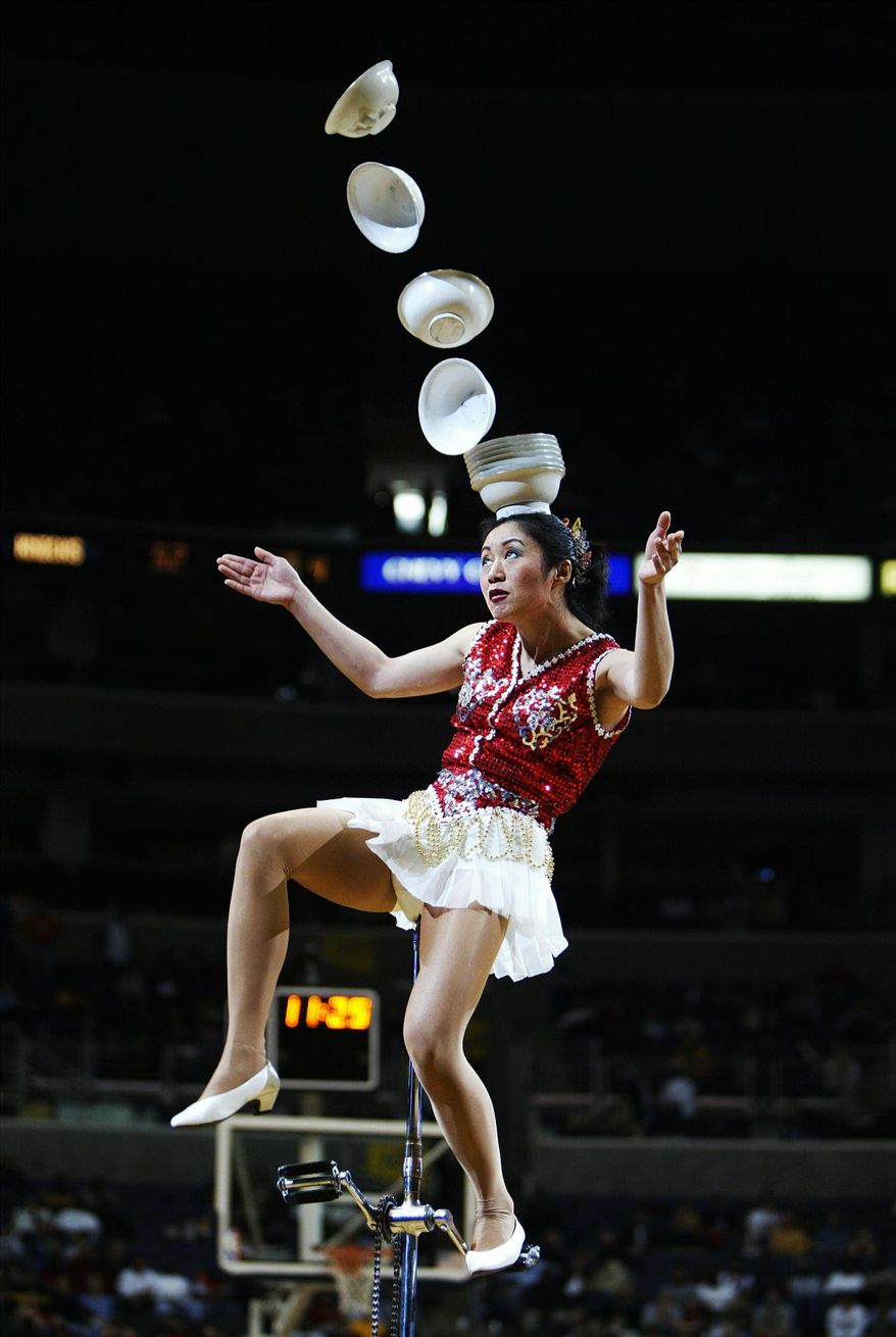 FILE - In this March 7, 2004 file photo, Rong Niu of China performs during the halftime break of the New York Knicks-Washington Wizards game by tossing the bowls with her right foot and catching them with her head as she balances on a unicycle in Washington. Someone at the San Francisco airport stole a 7-foot unicycle used by the Red Panda Acrobat for her plate-juggling routine and the legendary performer is offering a $2,000 reward to get it back. Police on Wednesday, Jan. 31, 2018, released surveillance photos from Jan. 24 that show a man wheeling away a black bag containing the $25,000 unicycle belonging to acrobat Rong Niu. (AP Photo/Manuel Balce Ceneta, File)