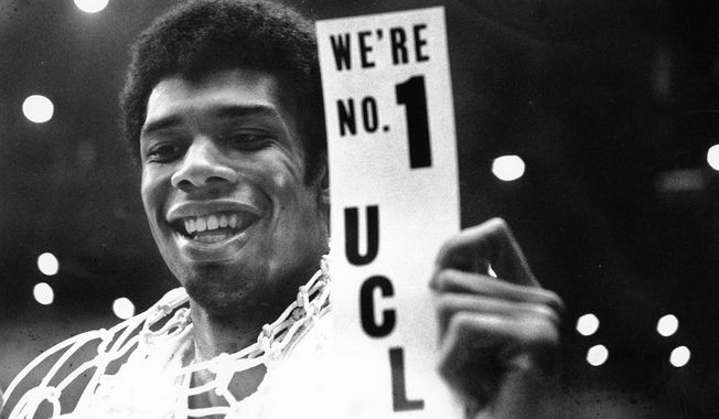 FILE - In this March 23, 1968, file photo, UCLA&#x27;s Lew Alcindor, with the basket netting draped over his shoulders, holds a sign just after leading UCLA to the NCAA basketball championship in Los Angeles on March 23, 1968.  Muhammad Ali’s actions influenced others. Alcindor boycotted the 1968 Summer Olympics. boycotted the 1968 Summer Olympics. After winning his first NBA championship in 1971, he took the Muslim name Kareem Abdul-Jabbar. (AP Photo/File)