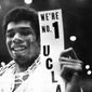 FILE - In this March 23, 1968, file photo, UCLA&#39;s Lew Alcindor, with the basket netting draped over his shoulders, holds a sign just after leading UCLA to the NCAA basketball championship in Los Angeles on March 23, 1968.  Muhammad Ali’s actions influenced others. Alcindor boycotted the 1968 Summer Olympics. boycotted the 1968 Summer Olympics. After winning his first NBA championship in 1971, he took the Muslim name Kareem Abdul-Jabbar. (AP Photo/File)