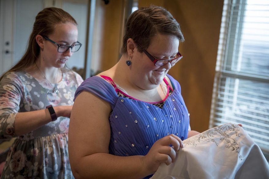 In a Jan. 22, 2018 photo, Hannah Simmons, left, assists Emily Gittins with the dress she recently picked out for the Night to Shine prom in North Ogden, Utah. Simmons, a student at Weber State University, and JoCee Porter run Celebrate Everyday, a nonprofit organization to donates prom dresses. (Benjamin Zack/Standard-Examiner via AP)