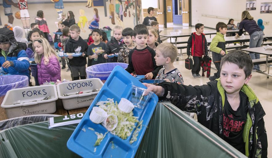 In a Jan. 26, 2018 photo, first-grader Alex Mundil dumps his tray into the composting bin after finishing lunch at Maxey Elementary School in Lincoln, Neb. The efforts at Maxey are just a piece of Lincoln Public Schools' efforts at sustainability. One of the programs that's grown considerably is composting, composting the waste from many of the 4.6 million lunches and 1.3 million breakfasts it serves. (Eric Gregory/The Journal-Star via AP)