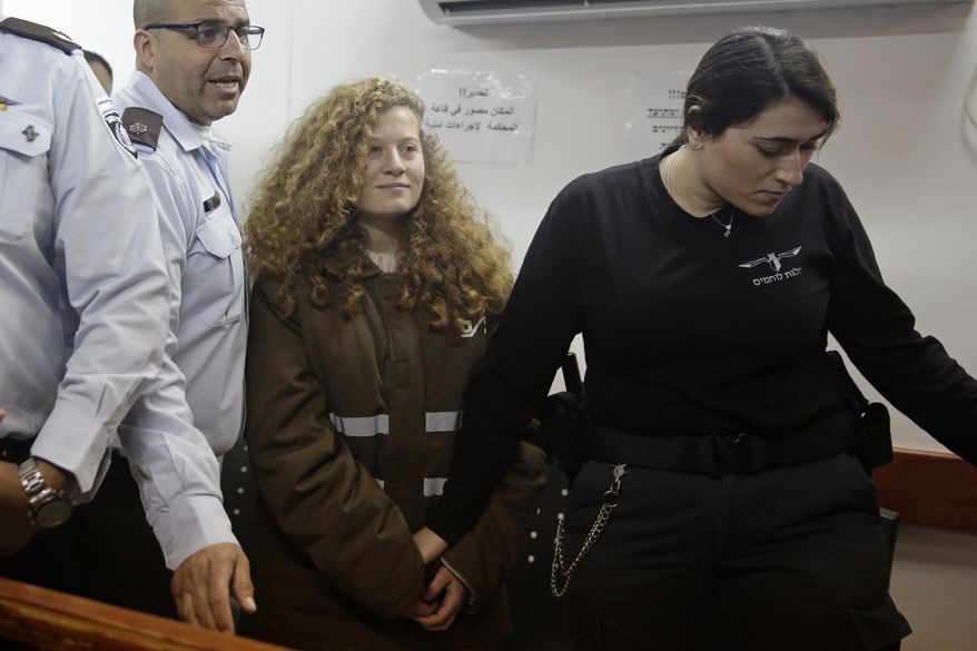 FILE - In this Jan. 15, 2018 file photo, Ahed Tamimi is brought to a courtroom inside the Ofer military prison near Jerusalem. A defense lawyer and Israel's military say the trial of Palestinian protest icon Ahed Tamimi before an Israeli military court has been postponed and is now scheduled to begin Feb. 13. (AP Photo/Mahmoud Illean, File)