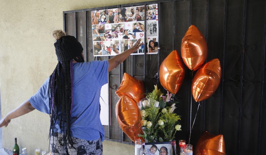 People gather around a memorial for a 16-year old boy fatally shot at an apartment complex courtyard during a police chase on Sunday night, in South Los Angeles, Monday, Feb. 5, 2018. A Los Angeles County sheriff's official says someone in a crowd that rushed in after a deputy fatally shot a teenager may have taken a gun from the suspect. (AP Photo/Damian Dovarganes)