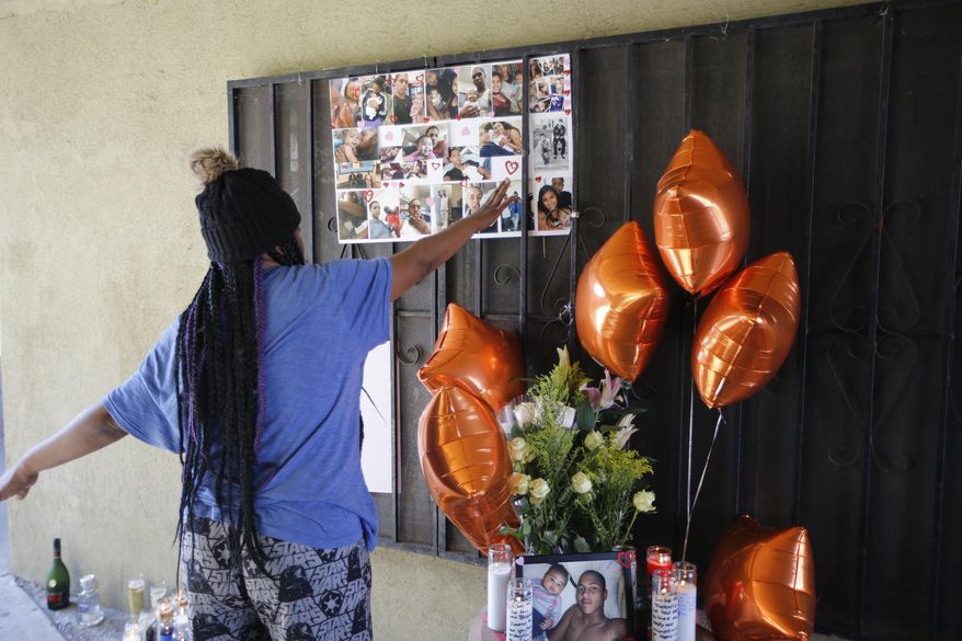 People gather around a memorial for a 16-year old boy fatally shot at an apartment complex courtyard during a police chase on Sunday night, in South Los Angeles, Monday, Feb. 5, 2018. A Los Angeles County sheriff's official says someone in a crowd that rushed in after a deputy fatally shot a teenager may have taken a gun from the suspect. (AP Photo/Damian Dovarganes)