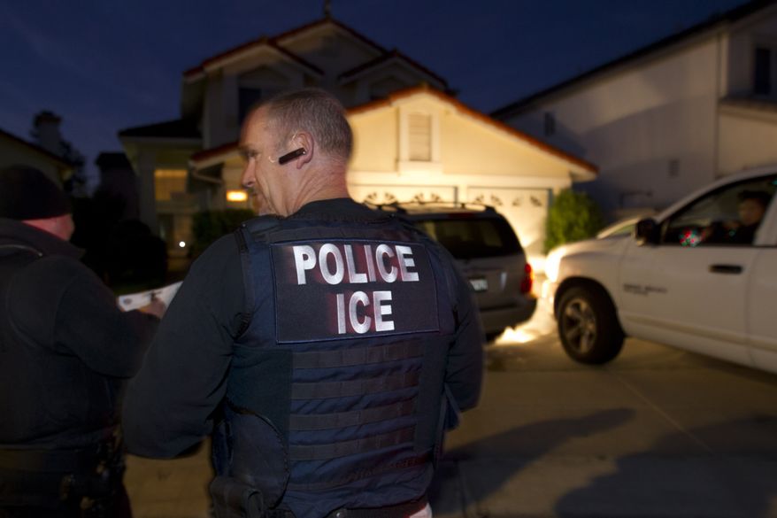 In this March 30, 2012 photo, an Immigration and Customs Enforcement (ICE) agent waits with other agents outside of the home of a suspect before dawn as part of a nationwide immigration sweep in San Diego. Federal officials say they arrested more than 3,100 immigrants convicted of serious crimes and fugitives in a six-day nationwide sweep. Officials at U.S. Immigration and Customs Enforcement say the sweep included every state and involved more than 1,900 of the agency’s officers and agents. (AP Photo/Gregory Bull)