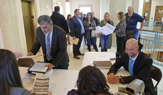Former Rep. Rick Miera of Albuquerque left foreground, and Rep. Bill McCamley of Mesilla Park, right, file declarations of candidacy to run for statewide office at the New Mexico Secretary of State&#x27;s Office in Santa Fe, N.M., on Tuesday, Feb. 6, 2018. Miera is running for lieutenant governor and McCamley is running for state auditor. The deadline arrived Tuesday for major party candidates in New Mexico to turn in nominating petitions in order to run for statewide or federal office. (AP Photo/Morgan Lee)