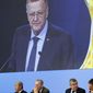 International Olympic Committee member and Court of Arbitration for Sport president John Coates is projected on a screen as he delivers a report on the Tokyo 2020 Summer Olympics during the 132nd IOC Session prior to the 2018 Winter Olympics in Pyeongchang, South Korea, Wednesday, Feb. 7, 2018. Pictured below Coates are Ugur Erdener of Turkey, from bottom left, Zaiqing Yu of China, former IOC President Jacques Rogge, IOC President Thomas Bach and Christophe De Kepper of Belgium. (AP Photo/Patrick Semansky)