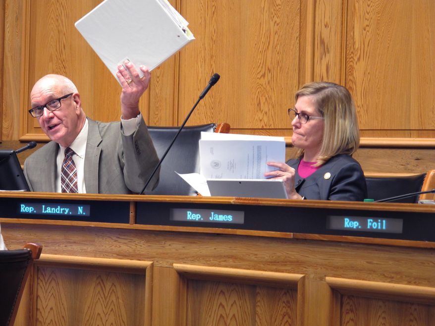 Sen. Dan "Blade" Morrish, R-Jennings, chairman of a task force studying Louisiana's TOPS college tuition program, holds the binder of information that was assembled for the group, while Rep. Nancy Landry, R-Lafayette, sifts through the data, on Wednesday, Feb. 7, 2018, in Baton Rouge, La. (AP Photo/Melinda Deslatte)