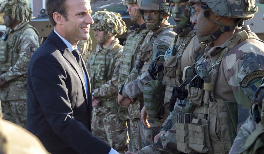 FILE - In this Friday, Sept. 29, 2017 file photo, France's President Emmanuel Macron, left, shakes hands with French soldiers of the NATO Battle Group at the Tapa military base, about 90 kilometers (56 miles) west of Tallinn, Estonia. French President Emmanuel Macron's government is unveiling a bill to boost military spending, notably amid demands by NATO and President Donald Trump for European countries to pitch in more for their own defense. (AP Photo/Marko Mumm, File)