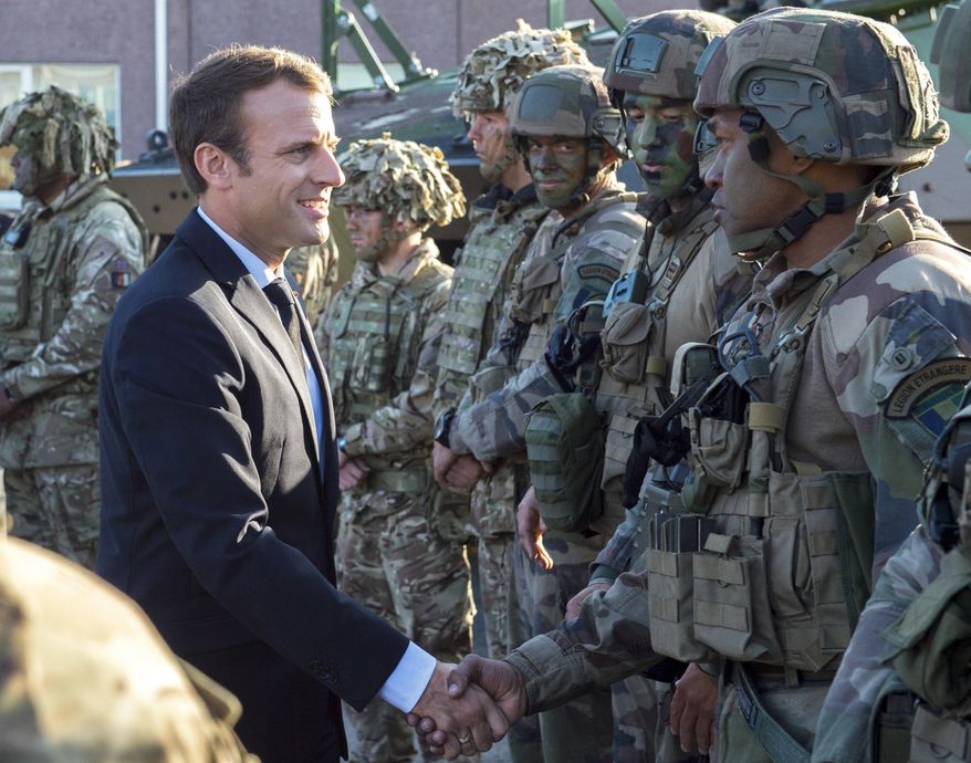 FILE - In this Friday, Sept. 29, 2017 file photo, France's President Emmanuel Macron, left, shakes hands with French soldiers of the NATO Battle Group at the Tapa military base, about 90 kilometers (56 miles) west of Tallinn, Estonia. French President Emmanuel Macron's government is unveiling a bill to boost military spending, notably amid demands by NATO and President Donald Trump for European countries to pitch in more for their own defense. (AP Photo/Marko Mumm, File)
