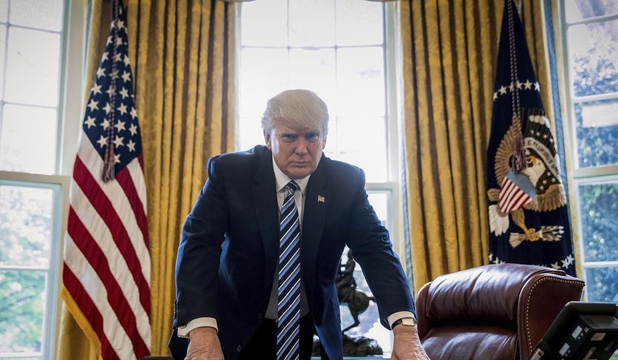 President Donald Trump poses at his desk in this Oval Office photo.