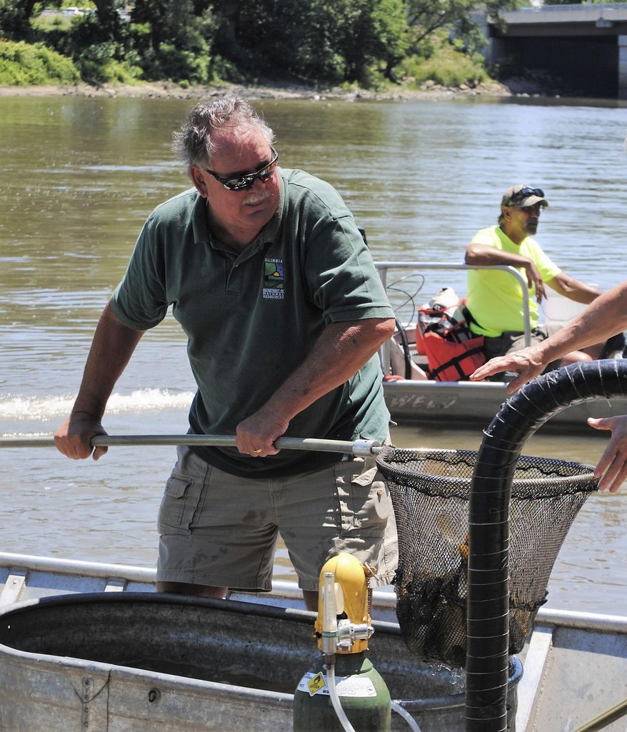 In this June 29, 2016 photo, now retired Mazonia-Braidwood Fish and Wildlife Area  Superintendent Mark Meents, hands off a dip net full of fish caught in Illinois Department of Natural Resources electro-fishing to be tagged as prize fish in the 33rd Annual Kakakekee River Fishing Derby in Kakakekee, Ill. Meents, retired Jan. 1, 2018 from the Illinois Department of Natural Resources after 39 years. (Robert Themer/The Daily Journal via AP)