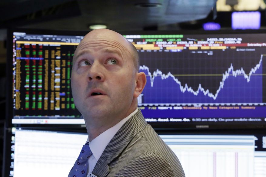 Specialist Jay Woods works at his post on the floor of the New York Stock Exchange, Friday, Feb. 9, 2018, as the chart behind him shows the day's Dow Jones industrial average volatility. (AP Photo/Richard Drew)
