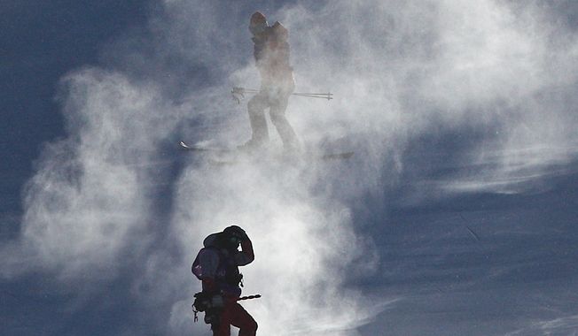 Course crew are shrouded in snow after the women&#x27;s giant slalom was postponed due to high winds on Monday. (ASSOCIATED PRESS)