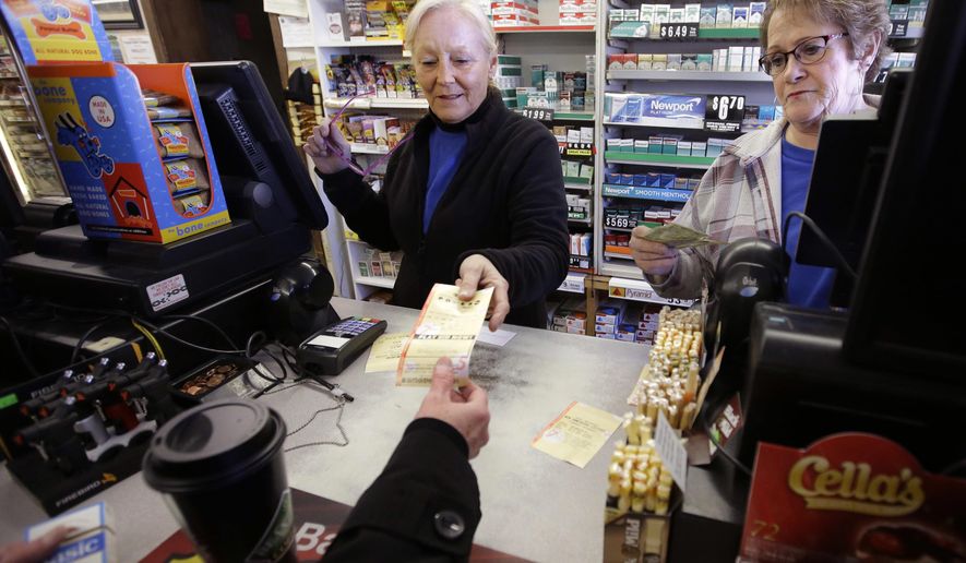 FILE - In this Jan. 7, 2018, file photo, cashiers Kathy Robinson, left, and Ethel Kroska, right, both of Merrimack, N.H., sell a lottery ticket at Reeds Ferry Market convenience store in Merrimack. A woman who bought the winning ticket there, and identified as in court documents as Jane Doe, won the $559.7 million jackpot and has filed a complaint in Nashua asking that a judge allow her to stay anonymous. The commission wants the complaint dismissed. The case will be heard Tuesday, Feb. 13. (AP Photo/Steven Senne, FIle)