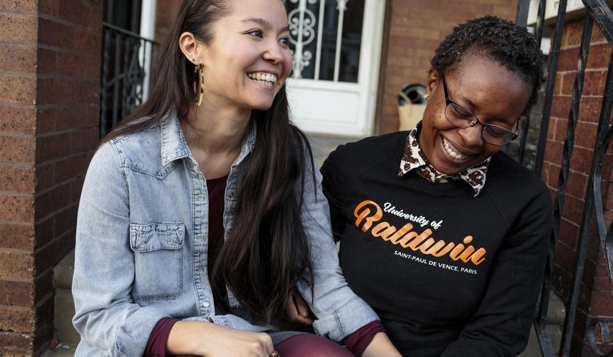 ADVANCE FOR USE THURSDAY, FEB. 15, 2018, AT 12:01 A.M. AND THEREAFTER -In this Nov. 11, 2017, photo, provided by Reveal, Rachelle Faroul, right, and her partner, Hanako Franz, sit outside their new home in Philadelphia. “I had a fair amount of savings and still had so much trouble just left and right,” said Faroul, who was rejected twice by lenders when she tried to buy a brick row house close to Malcolm X Park in Philadelphia. (Sarah Blesener/Reveal via AP)