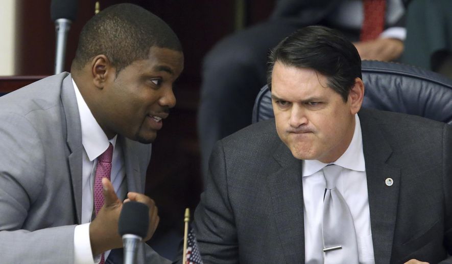 In this March 9, 2017, file photo, Rep. Byron Donalds, R-Naples, left, confers with Rep. Cord Byrd, R-Neptune Beach, in Tallahassee, Fla. Donalds is the lead sponsor of a proposal that would allow parents whose children have been bullied at public schools to obtain state vouchers to help pay tuition at a private school. (AP Photo/Steve Cannon, File)