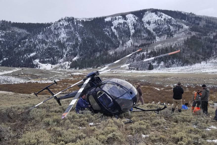 In this photo taken Monday, Feb. 12, 2018, and provided by the Wasatch County Sheriff's Office is a research helicopter that was brought down by a leaping elk in the mountains of eastern Utah. Wasatch County authorities say the elk jumped into the chopper's tail rotor as the craft flew low, trying to capture the animal with a net. The two people on board weren't seriously hurt, but wildlife officials say the elk died of its injuries. The state-contracted Australian crew had been trying to capture and sedate the elk so they could collar it and research its movements about 90 miles east of Salt Lake City. (Jared Rigby/Wasatch County Sheriff's Office via AP)