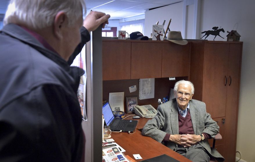 Frank Whitesell, right, who turned 100 years old Thursday, Feb. 8, 2018, and still goes to work every day, talks Tuesday to Morey Young, one of the businesses partners at Adprint, a company that makes promotional products for businesses on Tuesday, Feb. 6, 2018. (Dan Marschka/LNP via AP)