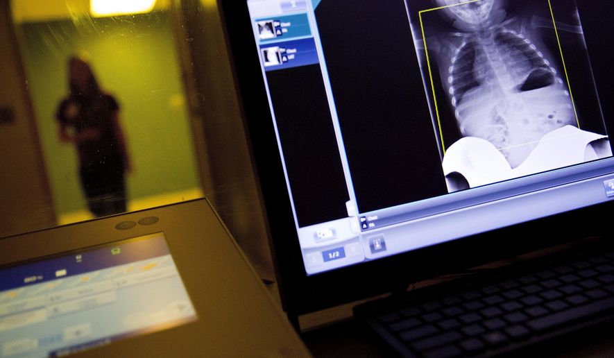 FILE- In this Feb. 9, 2018, file photo, a radiology technician looks at a chest X-ray of a child suffering from flu symptoms at Upson Regional Medical Center in Thomaston, Ga. A nasty flu season and fresh insurance deductibles may combine this winter to smack patients around the country with expensive medical bills. (AP Photo/David Goldman, File)