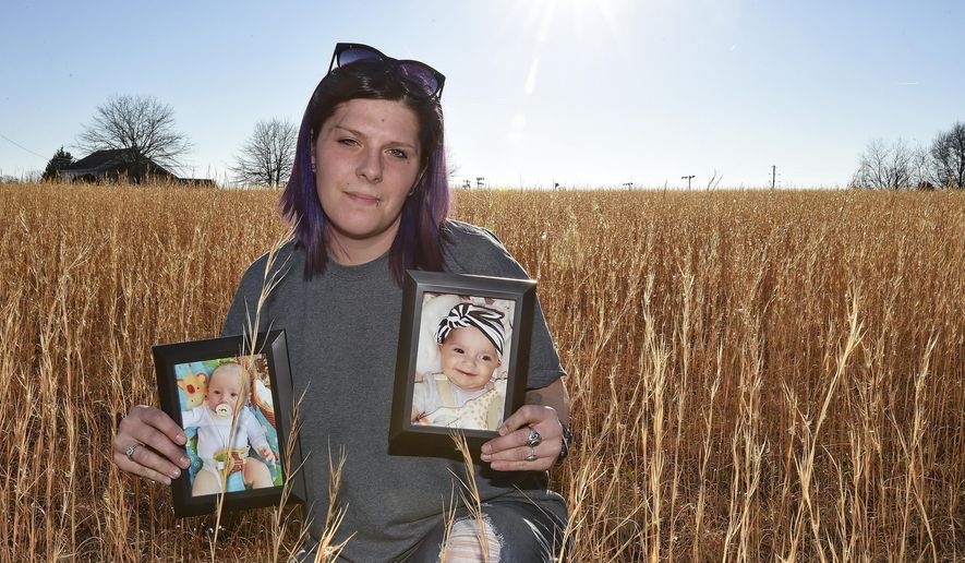 Sarah Sherbert poses for a photo in Anderson, S.C., on Monday, Feb. 5, 2018, holding photos of her children when they were infants. The two babies, born 15 months apart when she was overcoming opioid addiction, got two very different treatments at two different South Carolina hospitals. The different approaches highlight the fact that no one knows the best way to treat the opioid epidemic's youngest patients. (AP Photo/Richard Shiro)