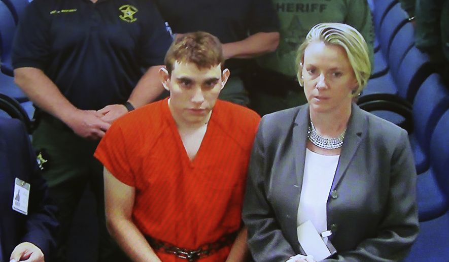 A video monitor shows school shooting suspect Nikolas Cruz, left, making an appearance before Judge Kim Theresa Mollica in Broward County Court, Thursday, Feb. 15, 2018, in Fort Lauderdale, Fla.  Cruz is accused of opening fire Wednesday at the school killing more than a dozen people and injuring several.   (Susan Stocker/South Florida Sun-Sentinel via AP, Pool)
