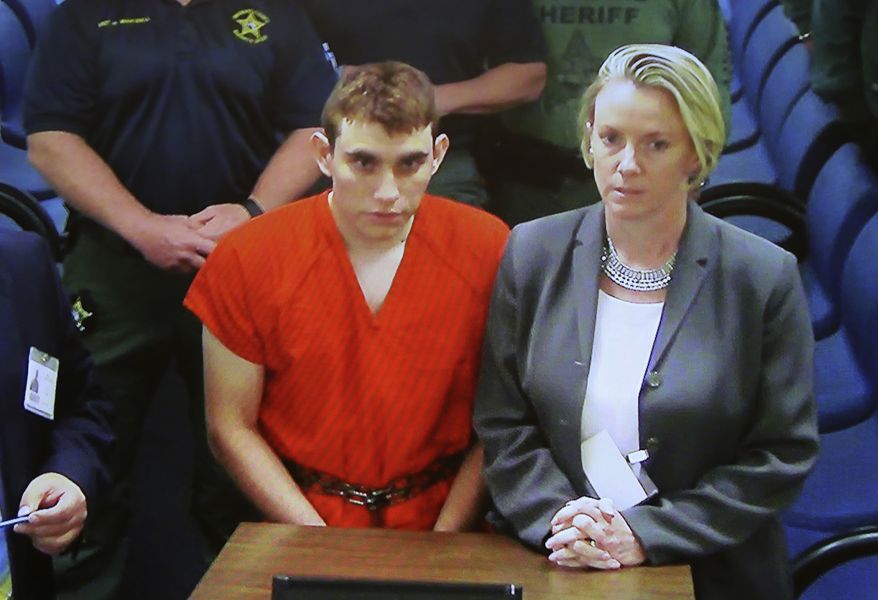 A video monitor shows school shooting suspect Nikolas Cruz, left, making an appearance before Judge Kim Theresa Mollica in Broward County Court, Thursday, Feb. 15, 2018, in Fort Lauderdale, Fla.  Cruz is accused of opening fire Wednesday at the school killing more than a dozen people and injuring several.   (Susan Stocker/South Florida Sun-Sentinel via AP, Pool)