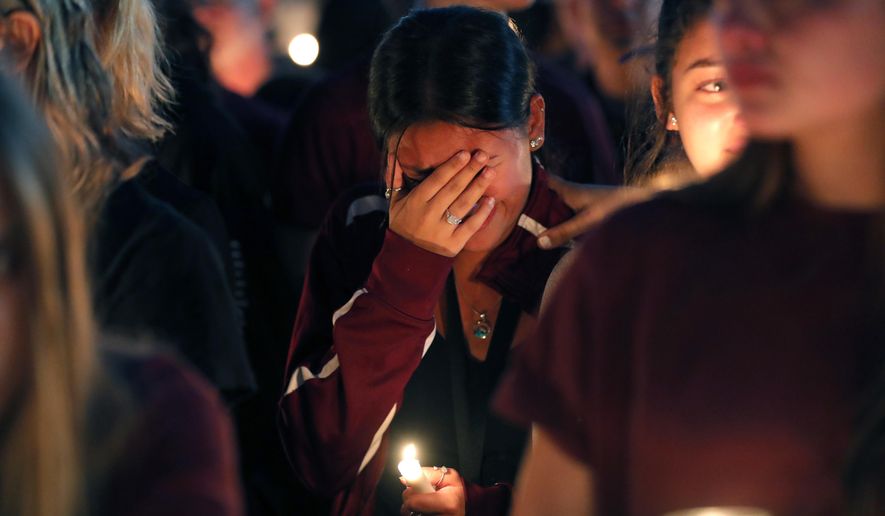 A woman cries during a candlelight vigil for the victims of the Wednesday shooting at Marjory Stoneman Douglas High School, in Parkland, Fla., Thursday, Feb. 15, 2018. Nikolas Cruz, a former student, was charged with 17 counts of premeditated murder on Thursday. (AP Photo/Gerald Herbert)