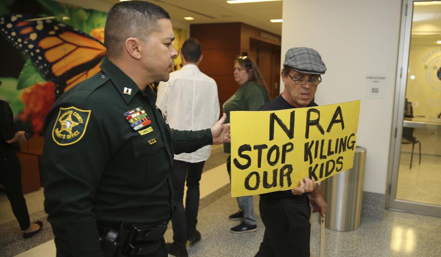 A Broward County sheriff's deputy escorts a protestor away from the door of the courtroom where a hearing was held for school shooting suspect Nikolas Cruz, Thursday, Feb. 15, 2018, at Broward County Court in Fort Lauderdale, Fla. Cruz is accused of opening fire Wednesday at Marjory Stoneman Douglas High School in Parkland, Fla., killing more than a dozen people and injuring several. (Charles Trainor Jr./Miami Herald via AP, Pool)