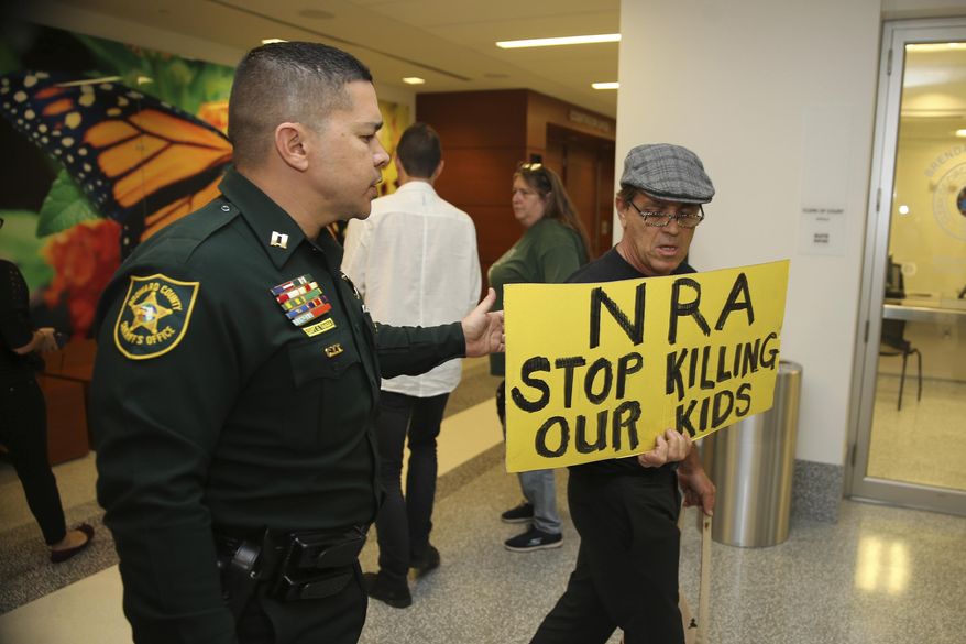 A Broward County sheriff's deputy escorts a protestor away from the door of the courtroom where a hearing was held for school shooting suspect Nikolas Cruz, Thursday, Feb. 15, 2018, at Broward County Court in Fort Lauderdale, Fla. Cruz is accused of opening fire Wednesday at Marjory Stoneman Douglas High School in Parkland, Fla., killing more than a dozen people and injuring several. (Charles Trainor Jr./Miami Herald via AP, Pool)