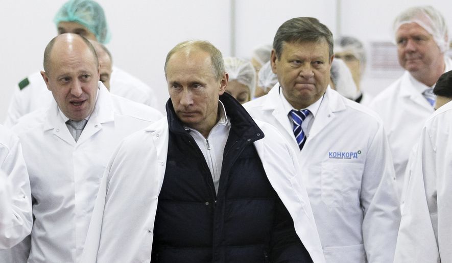 FILE - In this Monday, Sept. 20, 2010 file photo, Yevgeny Prigozhin, left, shows Russian Prime Minister Vladimir Putin, second left, around his factory which produces school meals, outside St. Petersburg, Russia. Progozhin is known as Putins chef _ a wealthy Russian businessman and restaurateur who gained favor with Putin through his stomach. On Feb. 16, 2016, Prigozhin, along with 12 other Russians and three Russian organizations, was charged by the U.S. government as part of a vast and wide-ranging effort to sway political opinion during the 2016 U.S. presidential election. According to the indictment, Prigozhin and his companies provided significant funding to the Internet Research Agency, a St. Petersburg-based troll farm that allegedly used bogus social media postings and advertisements fraudulently purchased in the name of Americans to influence the White House race. (Alexei Druzhinin, Sputnik, Kremlin Pool Photo via AP, File)