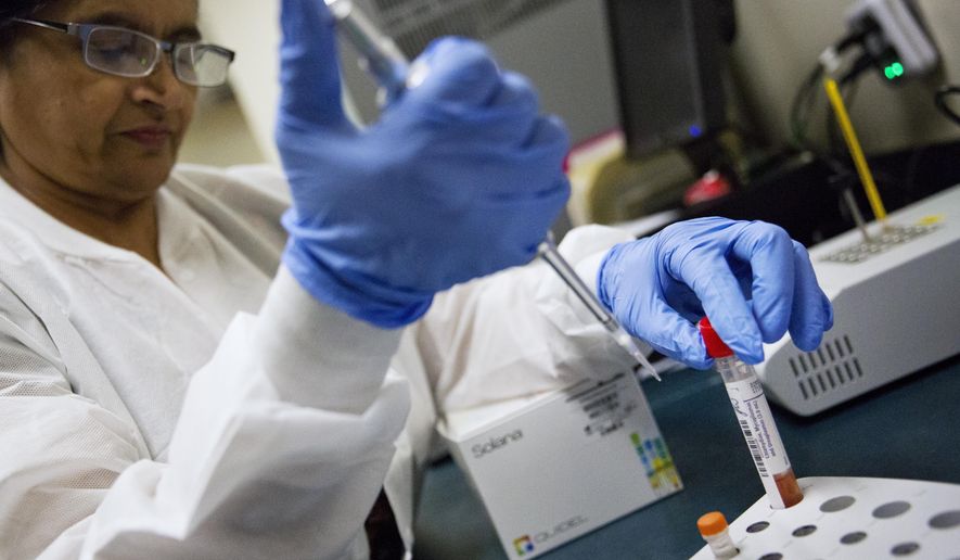 FILE - In this Friday, Feb. 9, 2018 file photo, lab technologist Sharda Modi tests a patient's swab for a flu infection at Upson Regional Medical Center in Thomaston, Ga. On Friday, Feb. 16, 2018, a report released by the Centers for Disease Control and Prevention shows the flu season may finally be leveling off. (AP Photo/David Goldman)