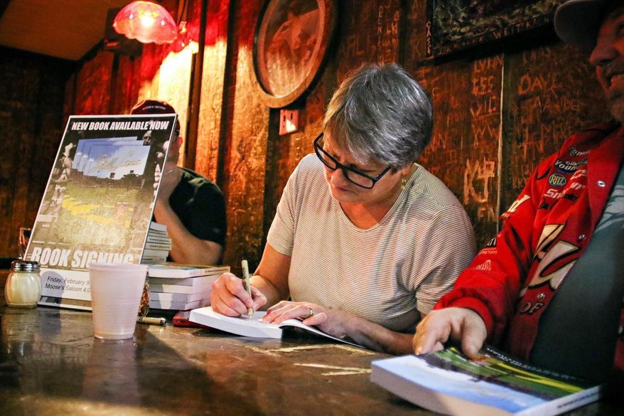 In this Feb. 9, 2018, photo, Lexie Miller Wyman signs copies of her book at Moose's Saloon in Kalispell, Mont. (Greg Lindstrom/Flathead Beacon via AP)