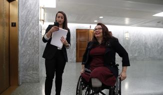 Sen. Tammy Duckworth, D-Ill., right, waits with an aide for the elevator on Capitol Hill, Wednesday, Feb. 14, 2018, in Washington. (AP Photo/Alex Brandon) ** FILE **