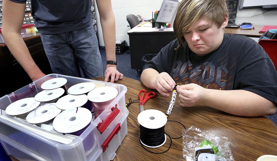 In this Feb. 13, 2018, photo, Onalaska High School senior Alexcie Luenger, 17, puts together a custom key chain, or Spirit Chain, during her jobs skills class at Onalaska High School in Onalaska, Wis. The class of special education students runs a small business called Ona Spirit to learn communication, budgeting and inventory skills. (Peter Thomson/La Crosse Tribune via AP)