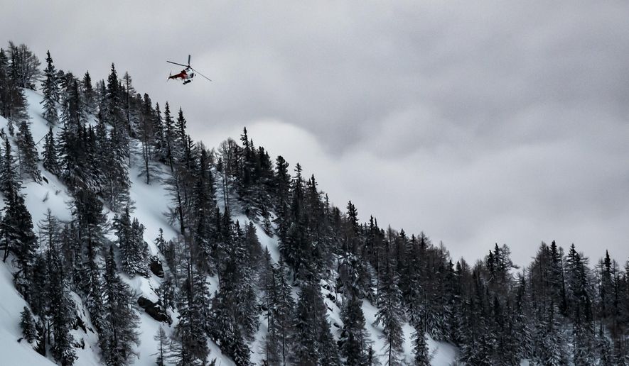 A helicopter leaves from the location where an avalanche left two people injured, at the Fenestral Pass, in Finhaut, Switzerland, Sunday, Feb. 18, 2018. Valais police spokesman Stefan Leger said Sunday that two people were hospitalized after being pulled from the snow. (Valentin Flauraud/Keystone via AP)